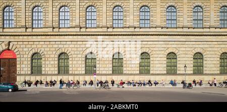 Sonnenanbeter sitzen auf der Treppe vor der Residenz am Max-Joseph-Platz an einem milden Februar Tag. [Automatisierte Übersetzung] Stockfoto