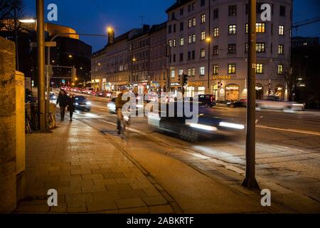 Straßenverkehr auf der Ludwigsbrücke Brücke in der Abenddämmerung. Im Hintergrund der Rosenheimer Berg und dem Gasteig. [Automatisierte Übersetzung] Stockfoto