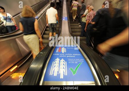 Ein neuer Aufkleber mit den Worten 'stand links und rechts, gehen Sie nicht dorthin! Helfen Sie uns, die Dinge schneller gehen' ist auf zwei Rolltreppen in der Mitte des Bahnsteigs der U-Bahnlinien 1 und 2 am Münchner Hauptbahnhof prangt. [Automatisierte Übersetzung] Stockfoto