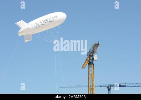 Zeppelin mit Werbung für die neue Konzerthalle oberhalb der Baustelle in der Fabrik Quartal hinter Ostbahnhof. Die neue Konzerthalle ist der Schauplatz des Symphonieorchesters des Bayerischen Rundfunks zu werden. [Automatisierte Übersetzung] Stockfoto