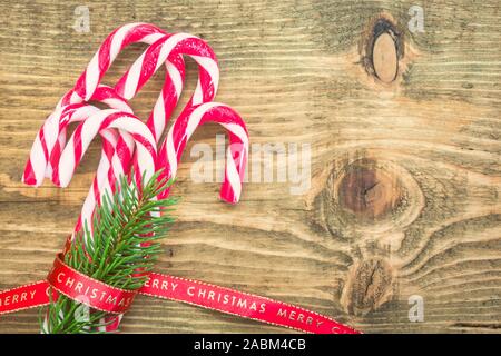 Zuckerstangen mit Red Christmas Band auf Holz- Hintergrund gewickelt. Vintage Farben Foto. Ansicht von oben mit der Kopie Raum auf der rechten Seite. Stockfoto