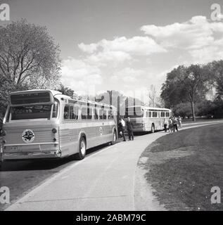 1950er Jahre, historisch, zwei Gray Line Reisebusse, geparkt an einer Straße neben einem öffentlichen Park, USA. Als führender Anbieter von Besichtigungstouren geht die Geschichte des Unternehmens auf das Jahr 1910 zurück, als Louis Bush begann, Touren durch Washington, D.C., mit einem renovierten alten, blau-grauen Mack-Truck anzubieten. Stockfoto