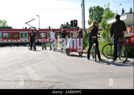 Radfahrer warten vor einer geschlossenen Schranke an der S-Bahn Kreuzung in Laim. [Automatisierte Übersetzung] Stockfoto