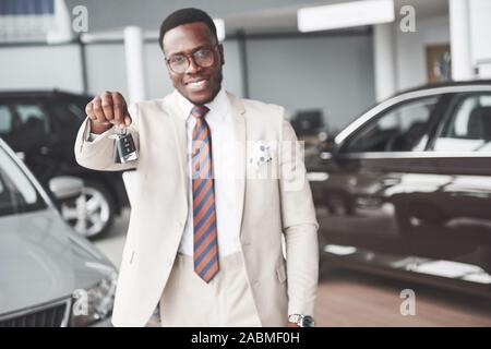 Die junge attraktive schwarze Unternehmer kauft ein neues Auto, er hält den Schlüssel in der Hand. Träume wahr werden Stockfoto