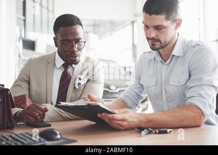 Eine junge attraktive schwarze Unternehmer kauft ein neues Auto, unterzeichnet er einen Vertrag und ist der Schlüssel zu den Manager Stockfoto