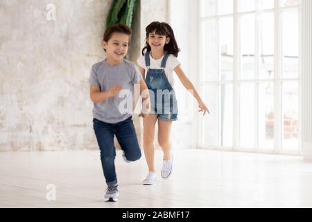 Begeistert junge und Mädchen haben Spaß im leeren Raum läuft Stockfoto