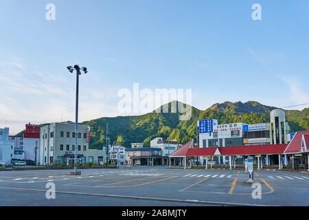 Die leeren Parkplatz, Berge, Bushaltestellen, Wartebereich, und Geschäfte außerhalb der Ausgang Ost von echigo-yuzawa Station auf einen späten Frühling Abend. Stockfoto