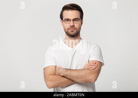 Ernsthaften tausendjährigen Mann in Gläser posiert mit verschränkten Armen Stockfoto