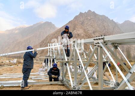 (191128) -- TAXKORGAN, November 28, 2019 (Xinhua) - Er Yaoming, ein Techniker aus dem Norden der Provinz Shanxi, China arbeitet auf der Baustelle Stromnetz Bau mit seinen Kollegen in Datong Gemeinde, Tadschikische Autonome Kreis Taxkorgan, Nordwesten Chinas Autonome Region Xinjiang Uygur, Nov. 24, 2019. Maryang Township und Datong Gemeinde sind im Pamir Plateau inmitten von hohen Bergen und tiefen Tälern, weit entfernt von der Kreisstadt entfernt. Für eine lange Zeit, das Gelände wird die langsame Entwicklung der Macht und andere Infrastruktur, die das größte Hindernis für die lokale Armut geworden Stockfoto