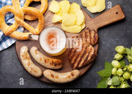 Oktoberfest. Brezeln, Würstchen, Fleisch und bier Bierkrug auf Stein Hintergrund. Ansicht von oben Stockfoto