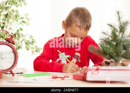 Kleiner Junge schreibt einen Brief an den Weihnachtsmann zu Weihnachten Geschenk und Wünsche Stockfoto