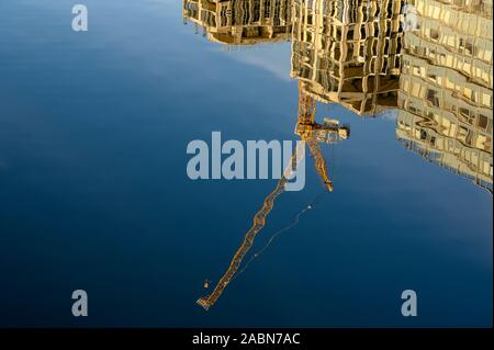 Baukran und Bürogebäuden im tiefblauen Wasser an einem sonnigen Tag wider. Stockfoto