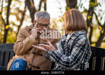 Senior Paar sitzt auf der Bank im Park und zu reden. Stockfoto