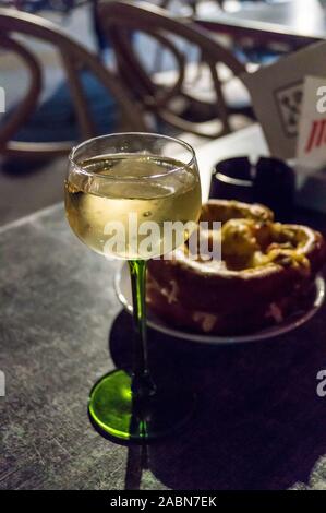 Ein Glas des Elsass Gewürztraminer Weißwein in seiner traditionellen Glas serviert mit Käse gefüllte Brezel, Straßburg, Elsass, Grand Est, Frankreich Stockfoto