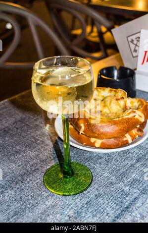 Ein Glas des Elsass Gewürztraminer Weißwein in seiner traditionellen Glas serviert mit Käse gefüllte Brezel, Straßburg, Elsass, Grand Est, Frankreich Stockfoto