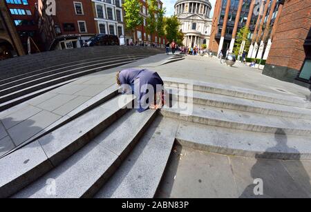 London, England, UK. Frau in Peter's Hill betteln, St Paul's Cathedral Stockfoto