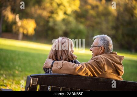 Romantische senior Paar sitzt auf der Bank im Park und genießen Sie den Herbst. Stockfoto