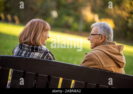 Romantische senior Paar sitzt auf der Bank im Park und genießen Sie den Herbst. Stockfoto