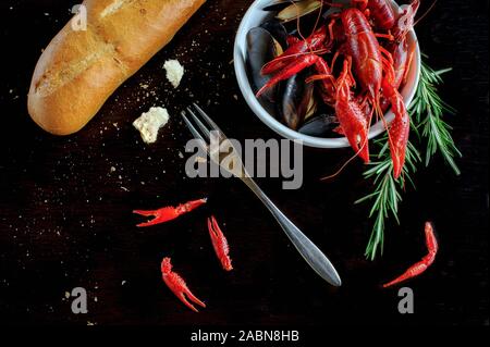 Frisch Hummer Nahaufnahme mit Zitrone, Knoblauch, Brot, Kräutern auf einem Schwarzen Tisch. Horizontal oben Ansicht von oben. Schöne plating und Dekorationen Stockfoto