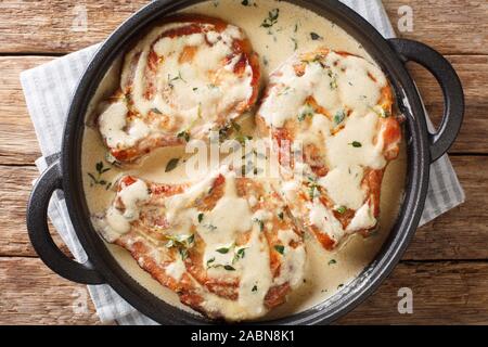 Ohne Knochen Schweinekoteletts in cremige Wein Sauce mit Kräutern in der Nähe serviert in einer Pfanne auf dem Tisch. Horizontal oben Ansicht von oben Stockfoto