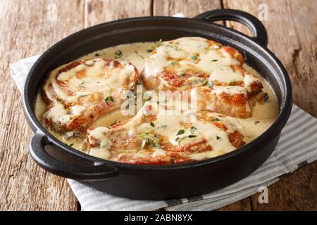 Ohne Knochen Schweinekoteletts in cremige Wein Sauce mit Kräutern in der Nähe serviert in einer Pfanne auf dem Tisch. Horizontale Stockfoto