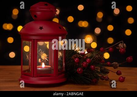 Red christmas Laterne und einer Kiefer brach auf einem Holztisch mit verschwommen Lichter im Hintergrund. Slective konzentrieren und Kopieren. Stockfoto