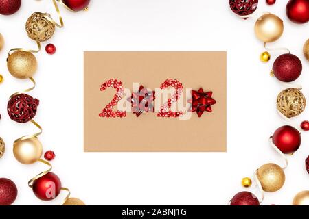 Frohes neues Jahr 2020. 2020 aus rotem funkelt und dekorative Weihnachten Spielzeug für das Handwerk Blatt Papier. Rahmen aus Weihnachten Kugeln. Stockfoto