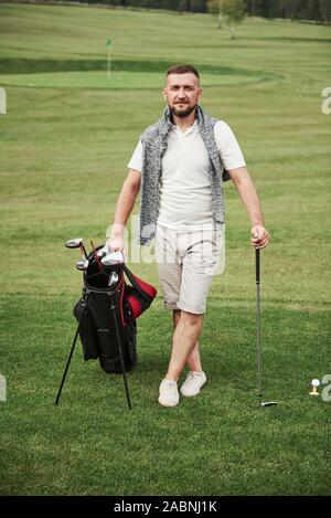 Ein professioneller Spieler steht auf einem Golfplatz, hält eine Tasche aus Metall und ein Golf Bag Stockfoto