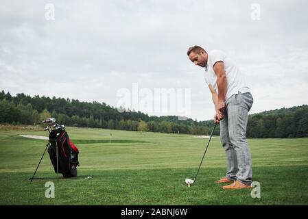 Pro Golf player Ziel geschossen mit Club auf Kurs. Männliche Golfspieler auf putting green Über die Hit zu nehmen Stockfoto