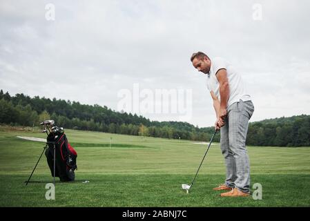 Pro Golf player Ziel geschossen mit Club auf Kurs. Männliche Golfspieler auf putting green Über die Hit zu nehmen Stockfoto