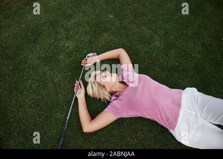 Das Mädchen liegt auf dem Golfplatz und entspannt nach dem Spiel Stockfoto