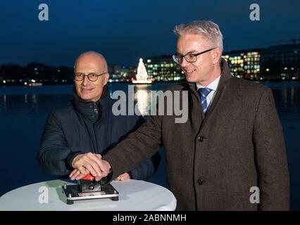 Hamburg, Deutschland. 28 Nov, 2019. Peter Tschentscher (SPD, l), erster Bürgermeister von Hamburg, und Sven-Olaf Schöpper, stellvertretender Leiter der Bezirksamt Hamburg-Mitte, die auf die Beleuchtung der traditionelle Weihnachtsbaum Schalter, den sogenannten Alstertanne auf der Binnenalster. Credit: Daniel Bockwoldt/dpa/Alamy leben Nachrichten Stockfoto