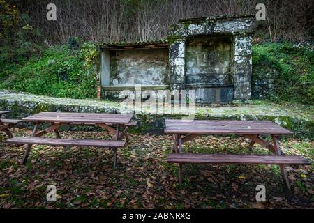 Brunnen mit zwei Holzbänken im Dorf von Pontito in der Via Santa Lucia unter dem Friedhof, Wandern entlang der Lucchese Apennin, Lucca, Toskana Stockfoto