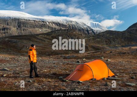 Mann neben Zelt mit Blick auf den Berg, Sinnitjohkka Kebnekaisefjaell, Norrbotten, Lappland, Schweden, September 2012 Stockfoto