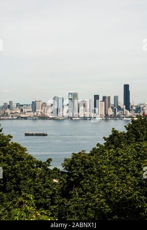 Umrahmt von Laub, eine Aussicht auf die Skyline von Seattle über dem Puget Sound, von West Seattle, Washington. Stockfoto