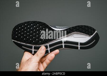 Paris, Frankreich, 24.Oktober 2019: Mann Hand gegen grauen Hintergrund neue professionelle Laufschuh manufatured Modell von Nike Air Zoom Pegasus 36 Schild Stockfoto