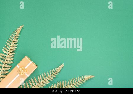 Festliche grüner Hintergrund mit gold Dekoration, Hintergrund mit Glitzer glänzenden goldenen Farnblätter und Geschenkboxen, Flach, Ansicht von oben, kopieren Raum Stockfoto