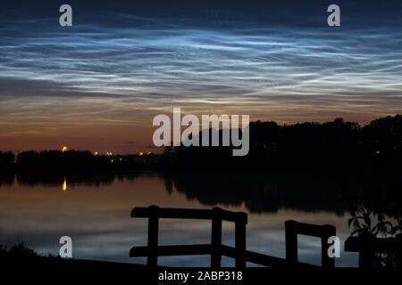 Nachtleuchtende Wolken (NLC, leuchtende Nacht Wolken) über einem See in Holland um Mitternacht. Stockfoto