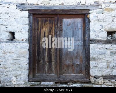 Verwitterte Holztür mit Holzbalken, die zwischen Schichten aus Stein in einem Altbau. Stockfoto