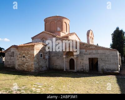 Apollonia, Albanien - 27. September 2019: Stein und Ziegel Fassade mit Torbogen und Kuppel der Kirche St. Maria. Gras Innenhof ist in den Vordergrund. Stockfoto