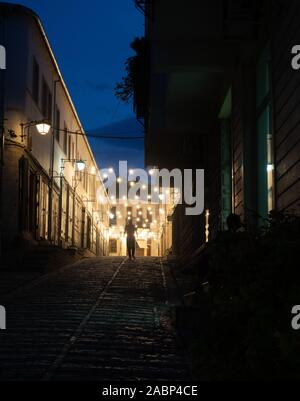 In Pogradec, Albanien - 26. September 2019: Straße in der Altstadt mit dem Menschen bis zu einer gepflasterten Straße bei Nacht mit dem Rücken zur Kamera. Str Stockfoto