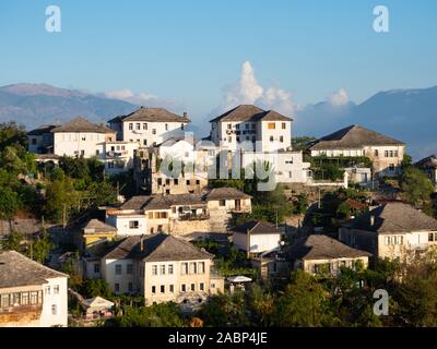 Gjirokastra, Albanien - September 26, 2019: Mehrere weiß getünchten, mehrstöckige Wohnhäuser auf einem Hügel. Gebäude haben Stein Dächer. Stockfoto