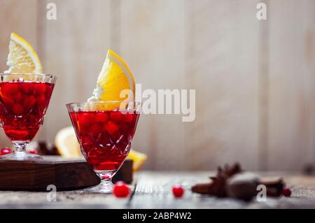 Zwei vintage Gläsern Glühwein mit Preiselbeeren, Orangenscheiben und Sternanis auf rustikalen Holztisch, Nahaufnahme Stockfoto