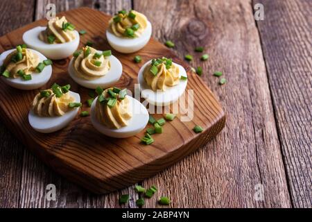 Russische Eier mit grünen Zwiebeln auf rustikalen Holzmöbeln Hintergrund, Ostern party Snack, Nahaufnahme Stockfoto