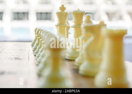 Weiße Stücke von Schach mit Unkonzentrierten Bauern und König und Königin im Fokus. Stockfoto