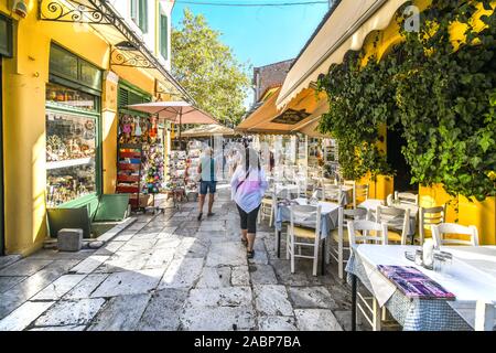 Touristen vorbei an Cafés und Geschäften durch die engen Straßen und Gassen in der touristischen Plaka Viertel im Herzen der Altstadt von Athen, Griechenland Stockfoto