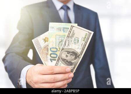 Mann im Anzug hält verschiedene Währungen. Geschäfts-, Finanz- und Gehalt Konzept Stockfoto