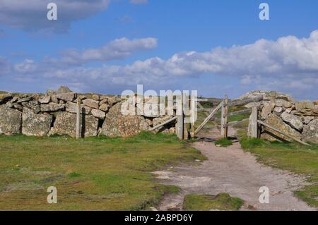 Große Granitsteine verwendet eine Mauer zwischen den Feldern in Cornwall zu bilden. kleine hölzerne Tor auf dem gut ausgetretenen Pfad., UK. Stockfoto