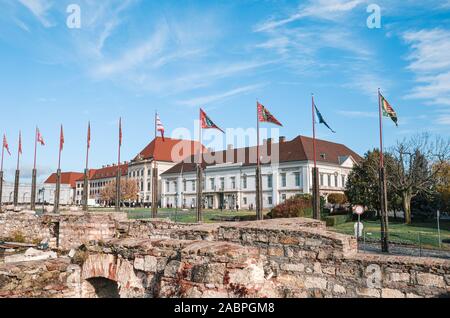 Wehenden Fahnen im Innenhof von Schloss Buda in Budapest, Ungarn. Sandor Palast, der Sitz des ungarischen Präsidenten, im Hintergrund. Wände Ruinen in den Vordergrund. Touristische Attraktion. Stockfoto