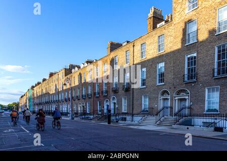 Radfahrer fahren auf dem Fahrrad neben georgianischen Häuser in Dublin, Irland. Sehenswürdigkeiten historische Architektur mit dem Fahrrad. Schatten auf der gegenüberliegenden Terrasse wider. Stockfoto